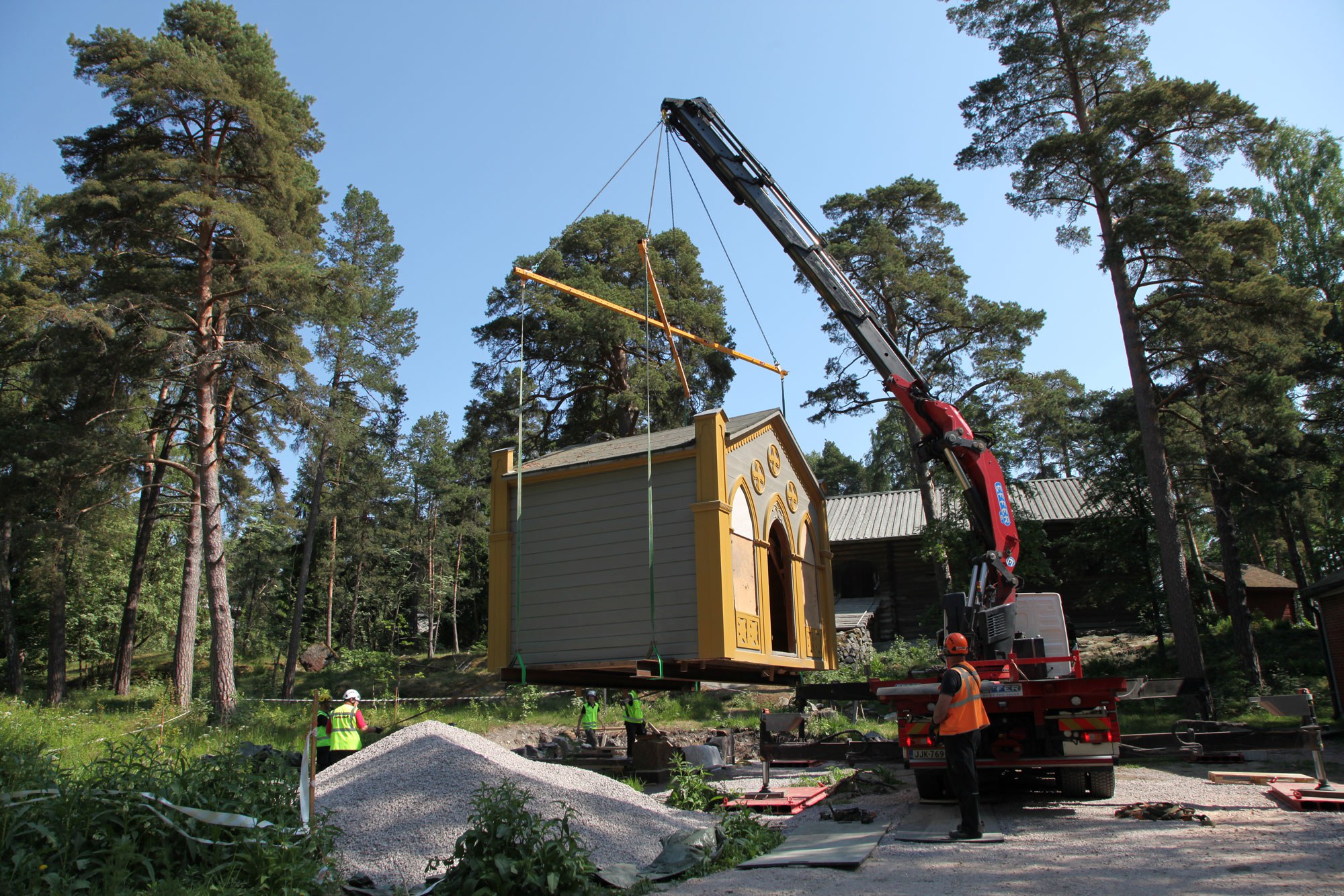 Huvimaja ilmassa siirtoköysien varassa. Vieressä huomioasuinen henkilö ohjaamassa.