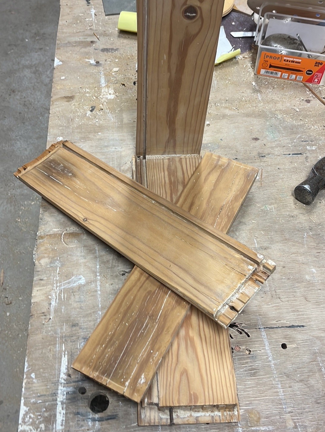 Työpöydällä on irrallisia vetolaatikon purettuja puuosia ja työkaluja keskeneräisessä puutyöprojektissa.