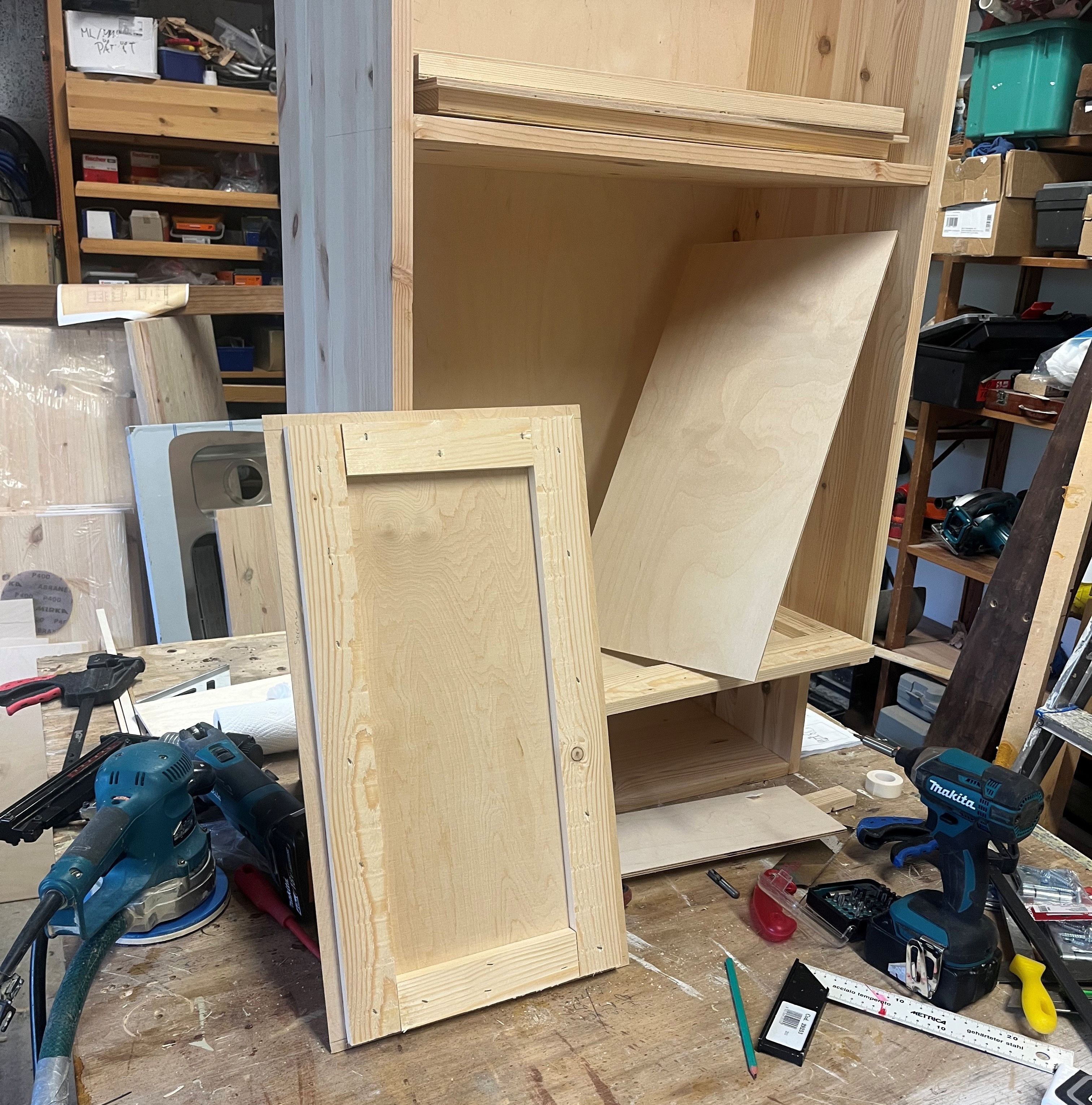Uuden yläkaapin kokopuinen runko ja vaneriovien osia maalaamattomina.
