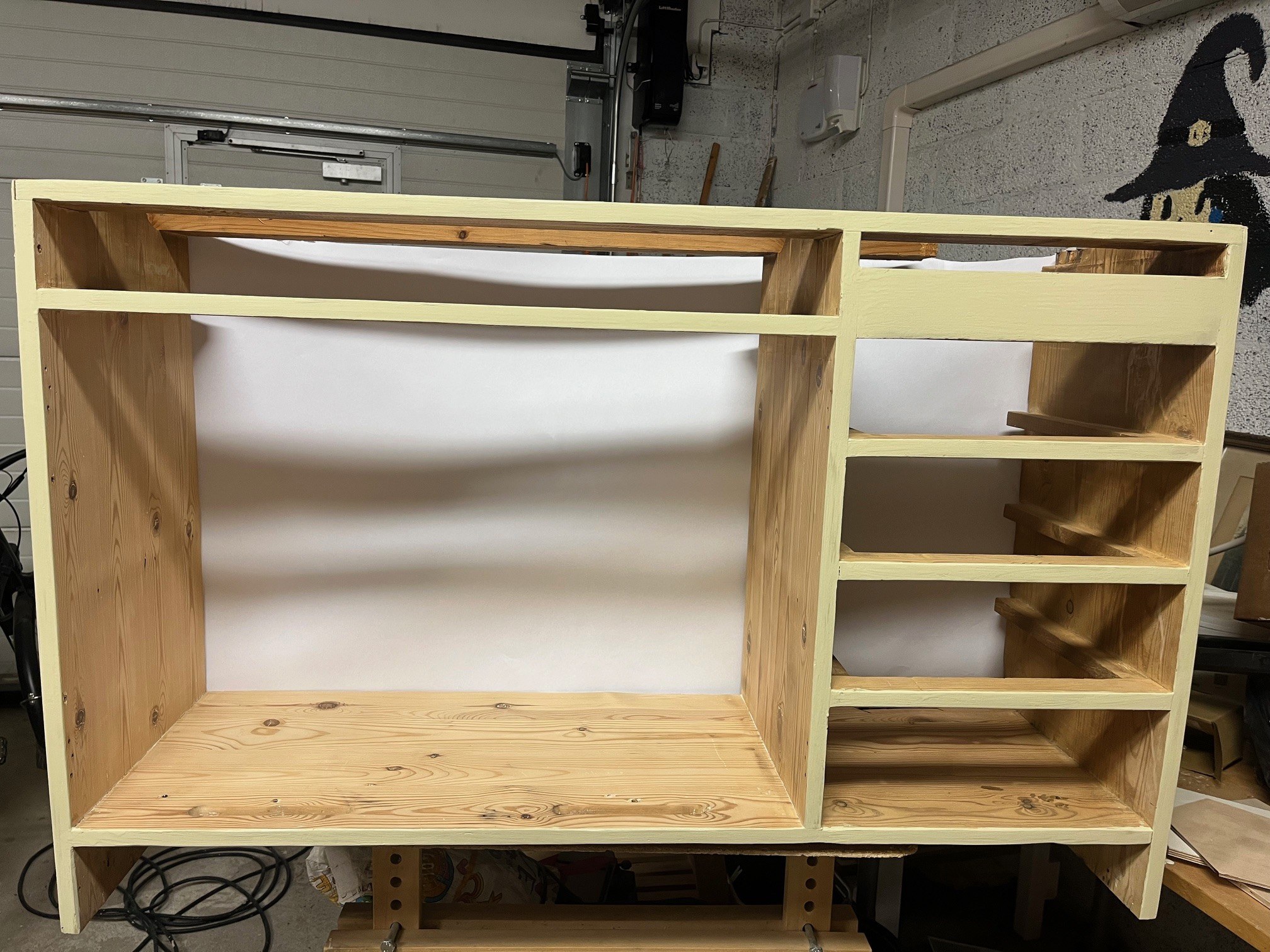 Vanha kokopuinen kaapinrunko verstaalla edestä päin nähtynä, näkyviin jäävästä etureunastaan maalattuna, ilman ovia ja vetolaatikoita.