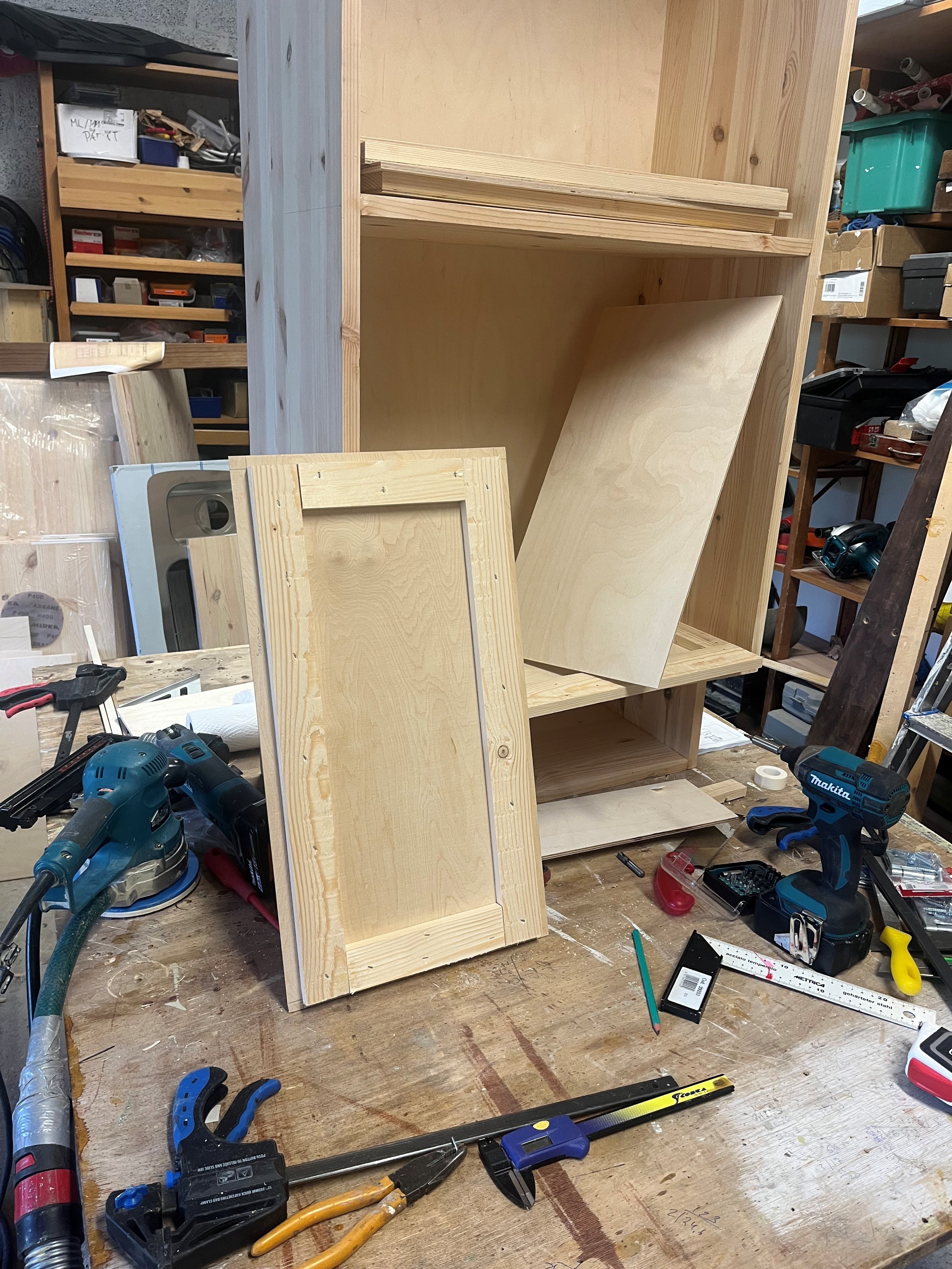 Uuden yläkaapin kokopuinen runko ja vaneriovien osia maalaamattomina.