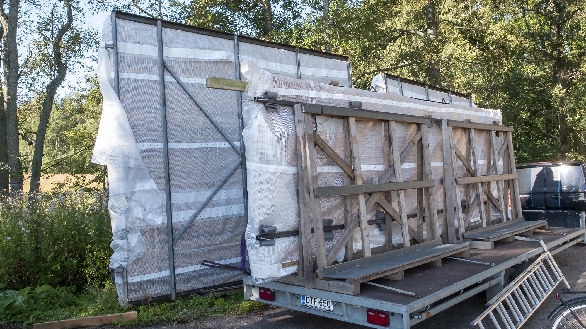 Auton peräkärry, jossa on suurikokoisia muoviin käärittyjä rakennusosaelemettejä.